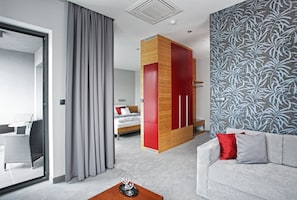Ett modernt hotellrum med en säng, en soffa, en matplats och ett stort fönster med gardiner.