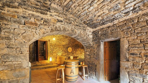 A stone-walled room with a wooden barrel, a small table, and a chair. - Cozy Stone House in the Aragonese Pyrenees (Boltaña)