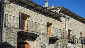 A stone building with balconies, wooden doors, and a tiled roof. - Cozy Stone House in the Aragonese Pyrenees (Boltaña)