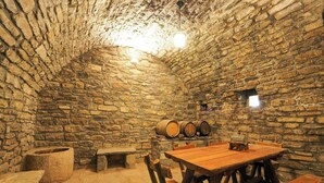A stone-walled cellar with wooden tables and benches, barrels, and a small window. - Cozy Stone House in the Aragonese Pyrenees (Boltaña)