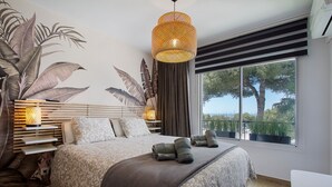 Una camera da letto moderna con un letto grande, un murales a parete, una lampada a sospensione e vista sull'esterno.