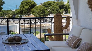 Un balcone con vista sul mare, un cactus e un tavolo con oggetti decorativi.