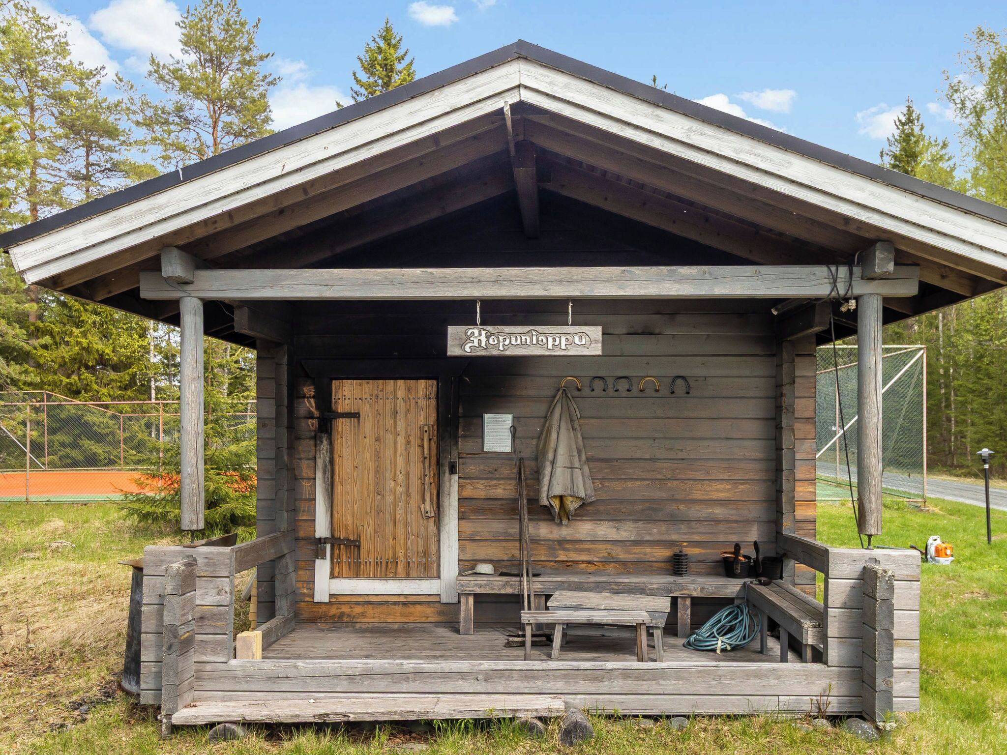 Une cabane en bois avec une véranda, une enseigne indiquant « Hopunloppu » et un banc.