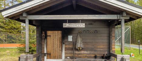 Une cabane en bois avec une véranda, une enseigne indiquant « Hopunloppu » et un banc.