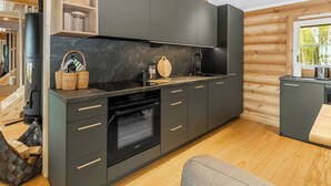 A modern kitchen with dark cabinetry, a built-in oven, and a wooden dining area.