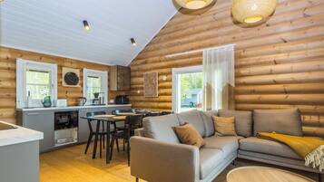 A log cabin interior with a dining area, sofa, and kitchen.