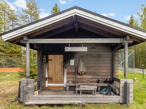 Une cabane en bois avec une véranda, une enseigne indiquant « Hopunloppu » et un banc.