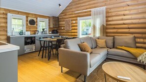 A log cabin interior with a dining area, sofa, and kitchen.