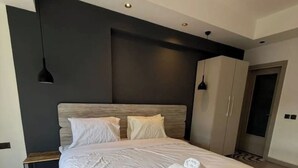 A modern bedroom with a large bed, a bedside table, a wardrobe, and a hanging light fixture.