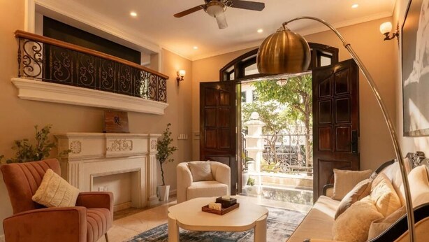 A living room with a fireplace, a sofa, a coffee table, and a view of the outside. - Super lovely Villa in Phu My Hung by Ray (Ho Chi Minh City)