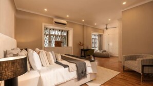 A bedroom with a bed, a bedside table, a lamp, a window with a decorative grille, and a door leading to another room. - Super lovely Villa in Phu My Hung by Ray (Ho Chi Minh City)