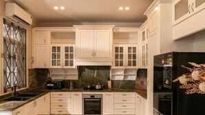 A modern kitchen with white cabinetry, a black refrigerator, and a granite countertop. - Super lovely Villa in Phu My Hung by Ray (Ho Chi Minh City)