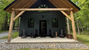 En stuga med en träfasad, en inglasad veranda och en svart dörr.