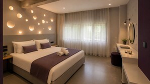 A modern bedroom with a large bed, bedside tables, a vanity with a mirror, and a window with sheer curtains. - Gold & Concrete Acropolis Residence (Athina)
