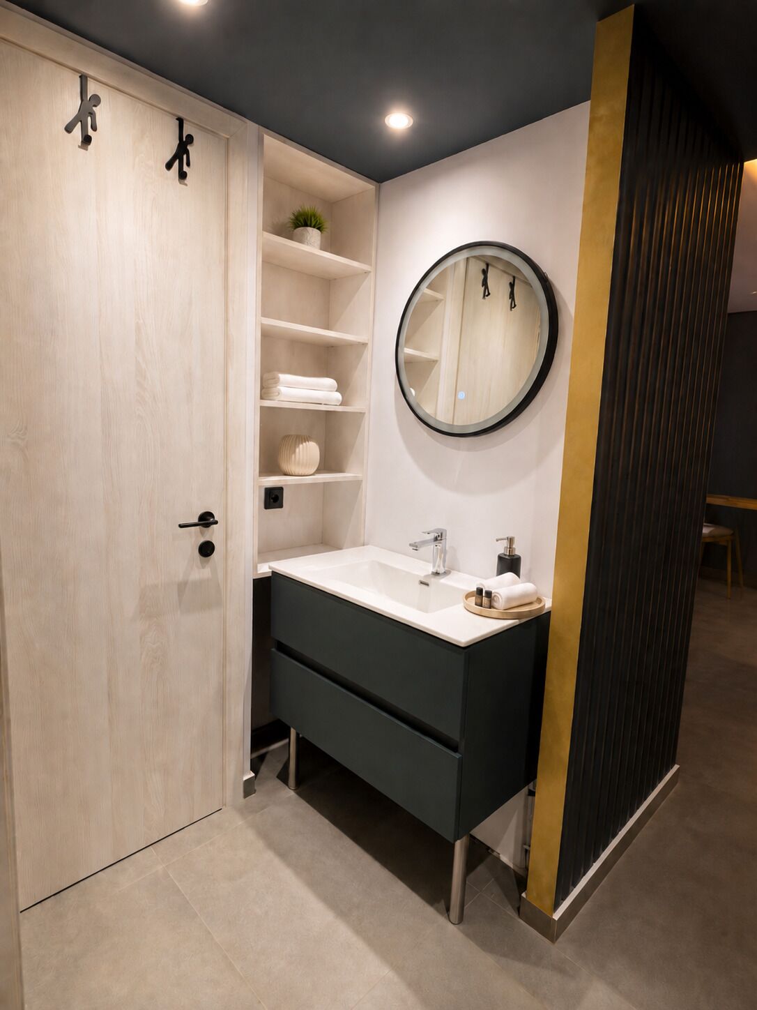 A modern bathroom with a white vanity, a round mirror, and a built-in shelf unit.