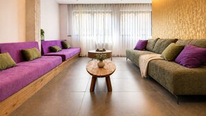 A modern living room with two sofas, a coffee table, and a view of a cityscape through large windows. - Gold & Concrete Acropolis Residence (Athina)