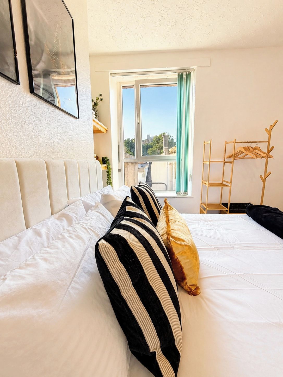 Een hotelkamer met een bed, een raam met uitzicht en een houten kapstok.
