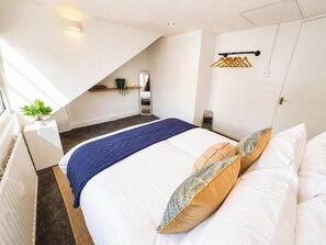 Un dormitorio con una cama, una mesita de noche, una lámpara colgante y una ventana.