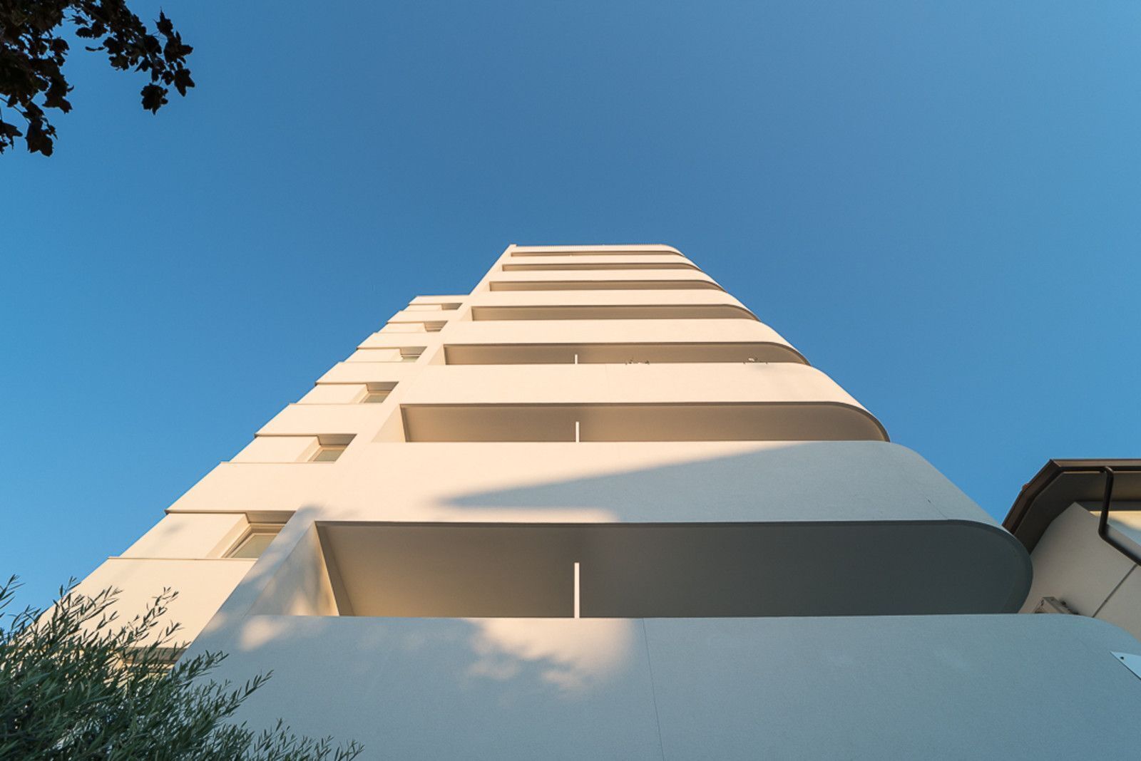 A modern building with a series of balconies and windows, viewed from the ground looking up.