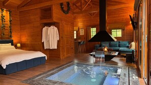 A log cabin interior with a bed, a seating area, a fireplace, and a hot tub. - Chalet for two (Delphi)