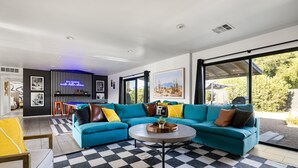 Ein modernes Wohnzimmer mit Schachbrettfußboden, einem smaragdgrünen Ecksofa und einem runden Couchtisch.
