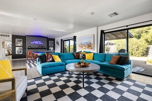A modern living room with a checkered floor, a teal sectional sofa, and a round coffee table. - Retro-chic home in Old Town Scottsdale! (Scottsdale)