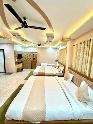 Una habitación de hotel con una cama grande, ventilador de techo, televisor y espejo.