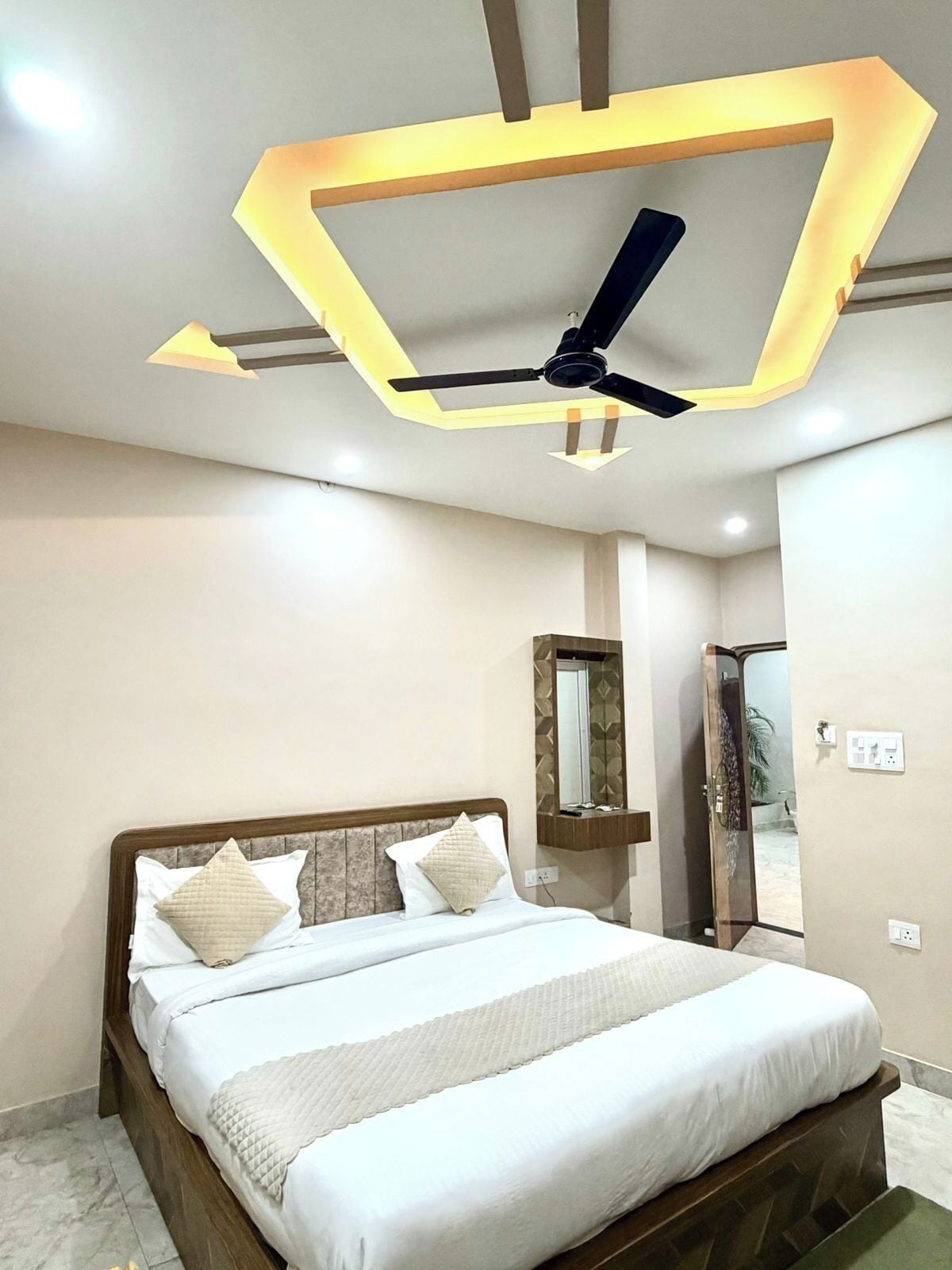 A modern bedroom with a bed, ceiling fan, and a unique ceiling design.