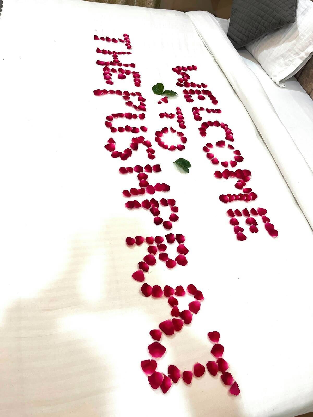 A bed with rose petals arranged in a heart shape.