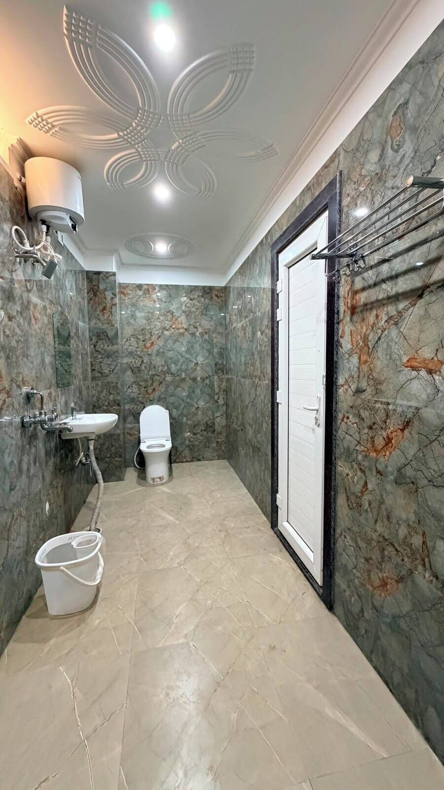 Un baño con piso de mármol, inodoro, lavamanos y zona de ducha.