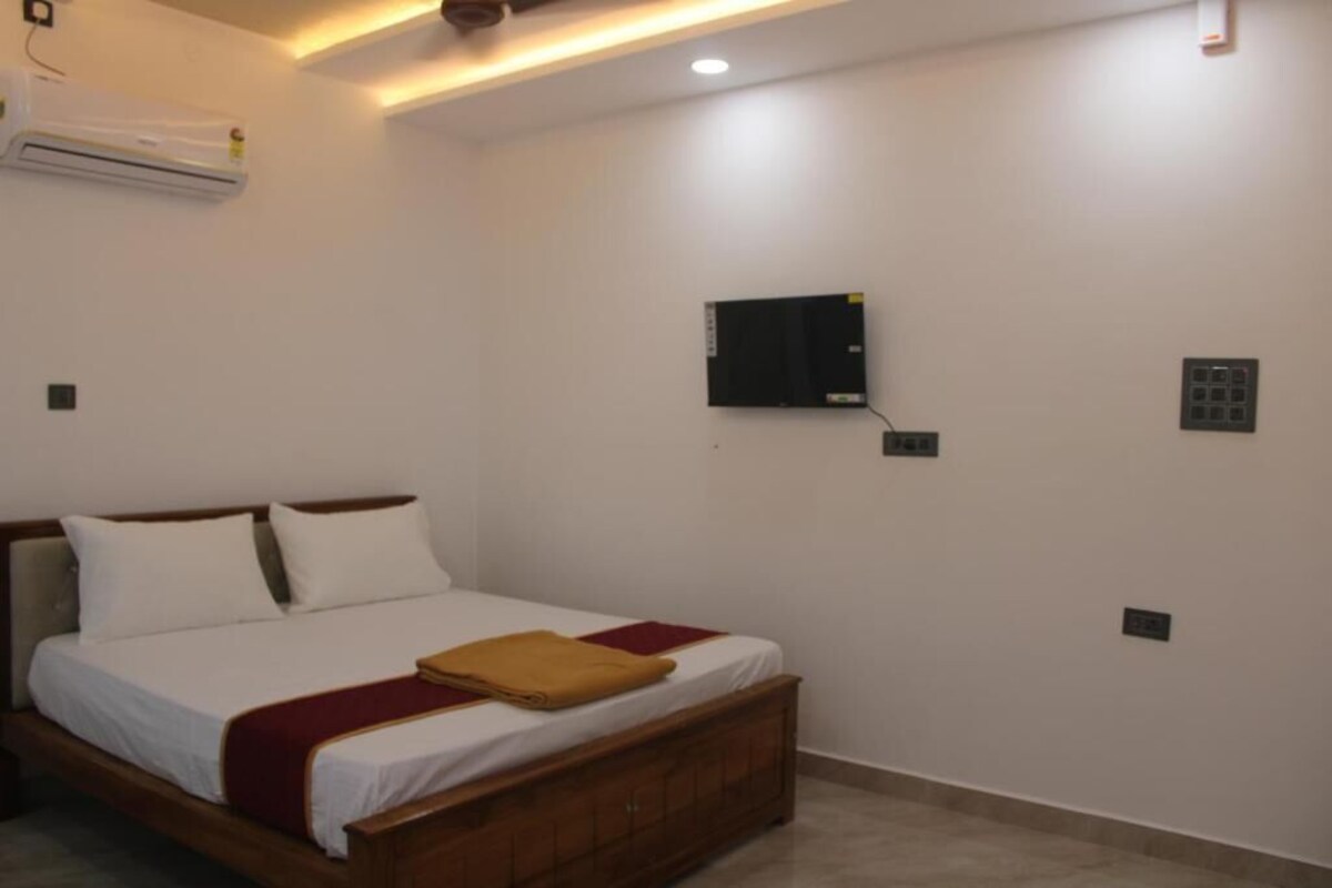 Un dormitorio con una cama, aire acondicionado de pared, televisor y panel de control.