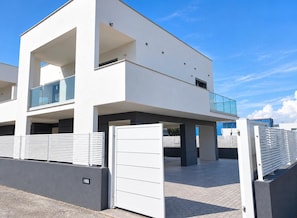 A modern two-story building with a balcony, a gated entrance, and a clear sky. - Casa Sole ,between Rome and the Sea. (Fiumicino)