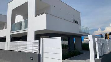A modern two-story building with a flat roof, large windows, and a gated entrance.