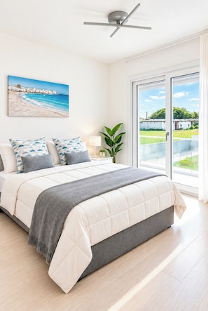 A bedroom with a bed, a ceiling fan, a window with a view, and a painting on the wall. - Casa Sole ,between Rome and the Sea. (Fiumicino)