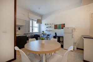 Eine moderne Küche mit weißen Schränken, einem runden Esstisch und einem Kühlschrank.
