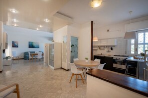 Een moderne keuken met een eethoek, witte kasten en een groot raam.