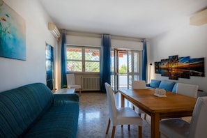Ein modernes Wohnzimmer mit einer Couch, einem Esstisch, Stühlen und Kunstwerken an den Wänden.