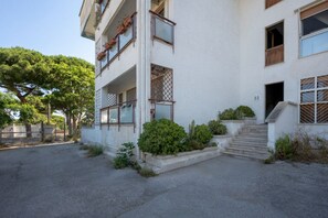 A multi-story building with a white exterior, a balcony on the second floor, and a small garden area with steps leading to the entrance. - GuestHost - Oasi Azzurra Apartment (Bari)