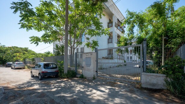Et lukket boligområde med parkerede biler og en bygning med flere etager.