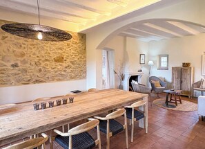 A rustic dining area with a wooden table, chairs, and a stone wall. - Peace and elegance in a Catalan country house with a pool, 3 km from the beach. (Torroella de Montgrí)