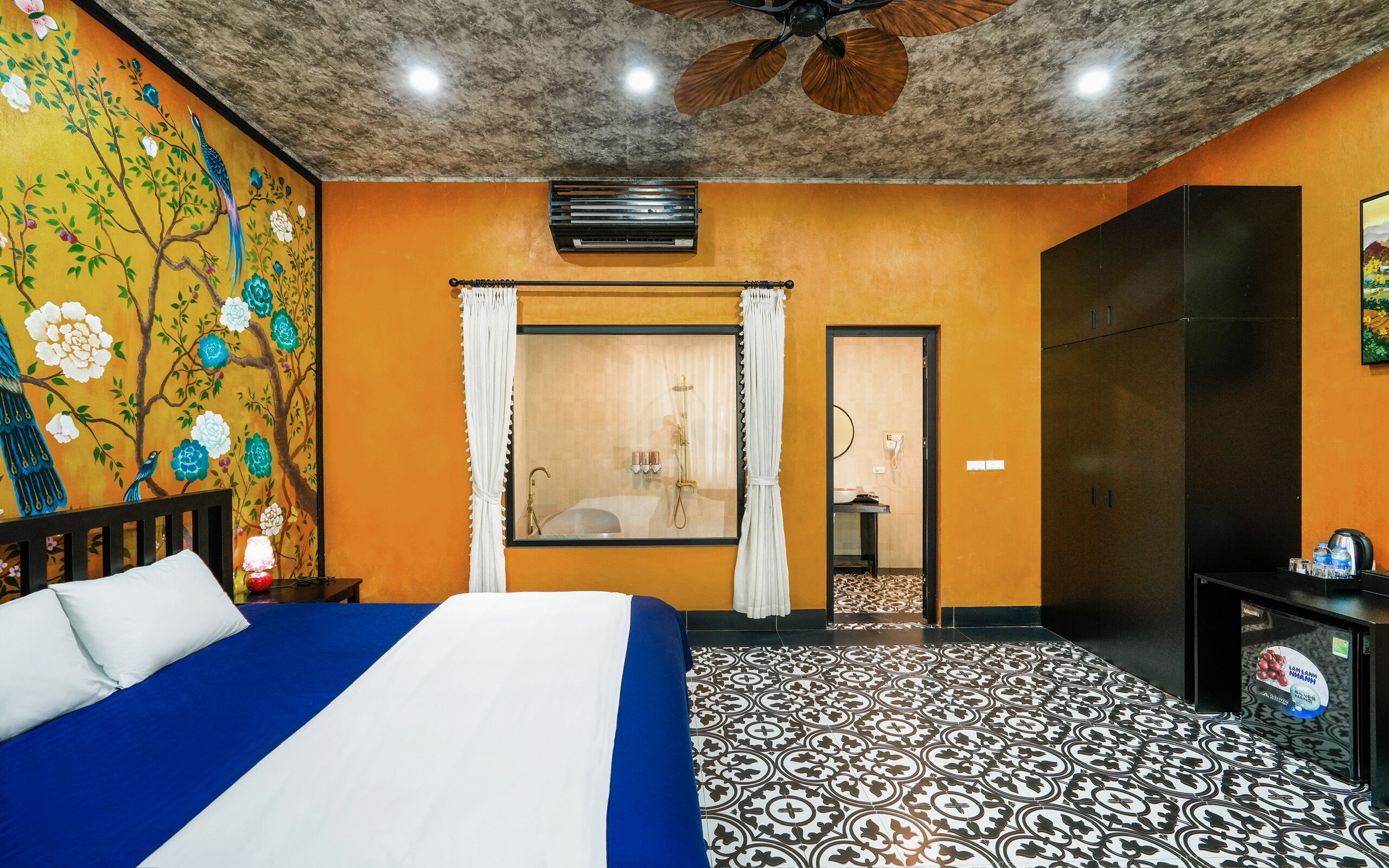 A hotel room with a bed, a shower, a wardrobe, and a decorative wall.