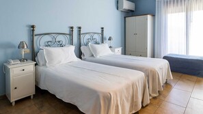 A hotel room with two beds, a wardrobe, a bedside lamp, and a telephone on the nightstand. - HOTEL NOVELLA (Benassal)