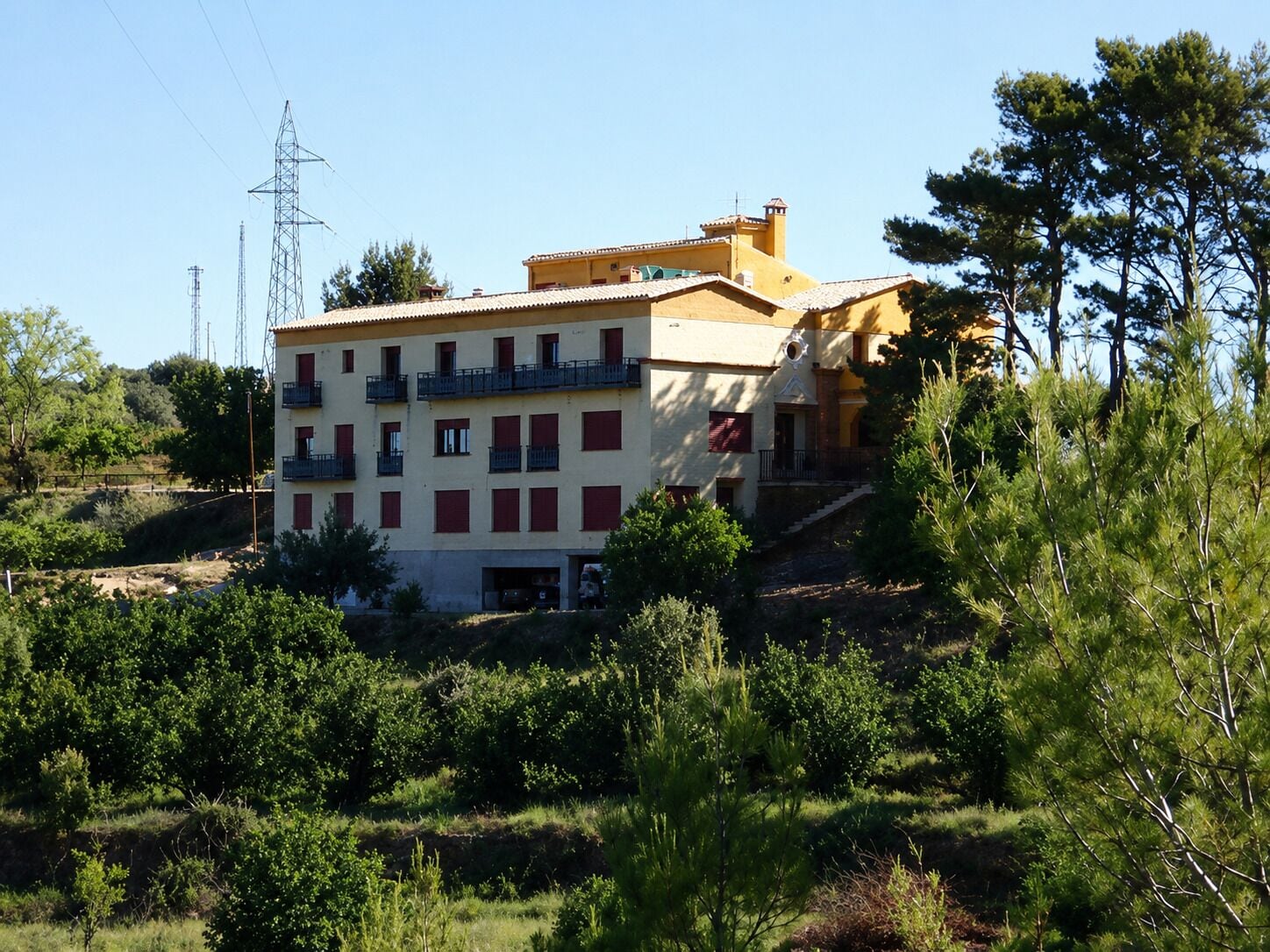 Um edifício com várias andares e varandas, rodeado por vegetação e árvores.