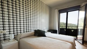Una camera d'albergo con un letto, un comodino, una finestra vista e una parete decorata.