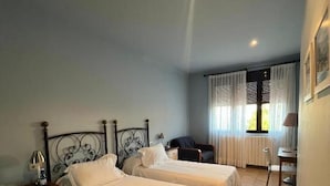 Una camera d'albergo con due letti, una scrivania, una sedia e una finestra con tende.