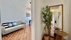 Un salon moderne avec un canapé, une plante en pot, un miroir et une petite table en bois.
