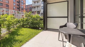A balcony with a table and chairs, a grassy area, and a view of multi-story buildings. - Beige and Blue Apartment | Garden | Parking (Gdańsk)
