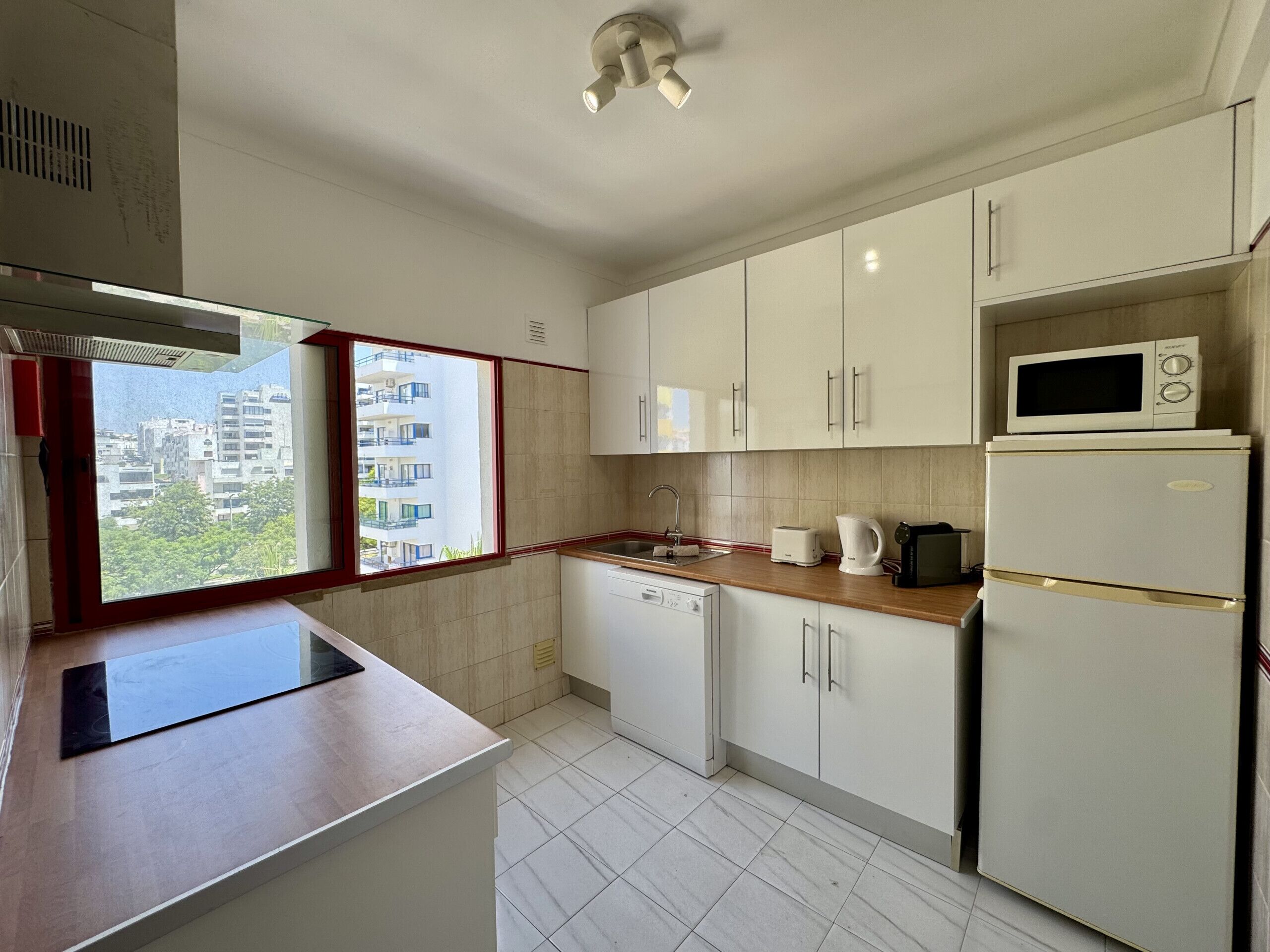 A modern kitchen with white cabinets, a microwave, a toaster, and a dishwasher.