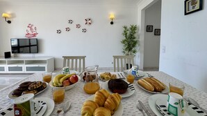 Ett frukostbord med tallrikar fyllda med mat, en kaffekopp och en tv-apparat i bakgrunden.