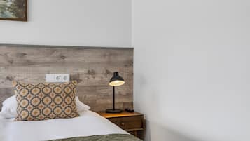 A neatly made bed with a patterned pillow, a bedside lamp, and a wooden headboard.
